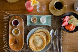 a table with pancakes and fruit and a cup of coffee at The Bed by The Sea in Canggu