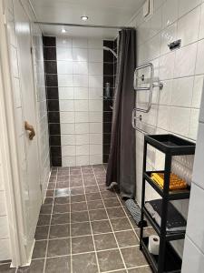 La salle de bains est pourvue d'une douche et de carrelage. dans l'établissement Rymlig lägenhet i Stenungsund, à Stenungsund