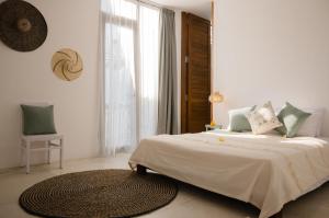 a white bedroom with a bed and a large window at The Bed by The Sea in Canggu