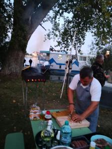 un hombre preparando comida en una tabla de cortar en una mesa de picnic en Hotel plutitor Sofia-Maria en Uzlina