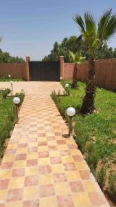 a brick walkway with a palm tree and a fence at Villa privative tortues2 piscine individual 35min in Marrakesh