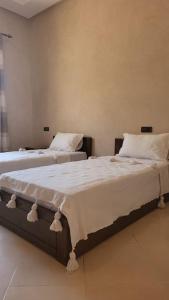 1 dormitorio con 2 camas con sábanas blancas en Villa privative tortues2 piscine individual 35min, en Marrakech