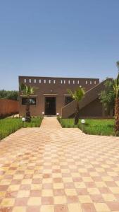 a brick walkway leading to a building with palm trees at Villa privative tortues2 piscine individual 35min in Marrakech