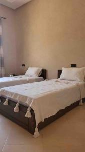 1 dormitorio con 2 camas con sábanas y almohadas blancas en Villa privative tortues2 piscine individual 35min, en Marrakech