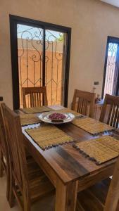 een houten tafel met stoelen en een bord eten erop bij Villa privative tortues2 piscine individual 35min in Marrakesh