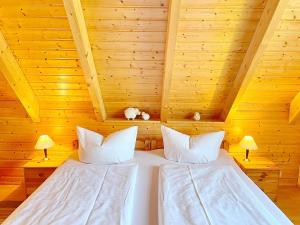 a bed in a wooden room with two pillows at Ferienhaus Eisvogel in Lübbenau
