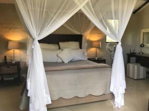a bedroom with a canopy bed with white curtains at Leadwood Tree Safari Lodge - Tamboti Lodge 45 in Belgrade