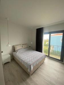 ein weißes Schlafzimmer mit einem Bett und einem großen Fenster in der Unterkunft Moderne Villa in Kuşadası in Kusadası