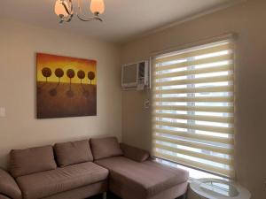 a living room with a couch and a window at Homey 2 BR Unit w/Pool in Avida IT Park in Cebu City