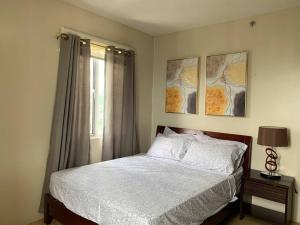 a bedroom with a bed and two paintings on the wall at Homey 2 BR Unit w/Pool in Avida IT Park in Cebu City +14 photos