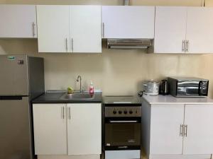 a kitchen with white cabinets and a sink and a microwave at Homey 2 BR Unit w/Pool in Avida IT Park in Cebu City