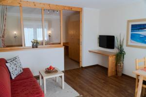 a living room with a red couch and a tv at Chalet Alpenblick in Fiss