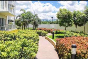 een loopbrug door een tuin met bloemen en bomen bij Homey 2 BR Unit w/Pool in Avida IT Park in Cebu City