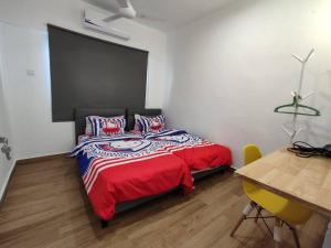 una camera con un letto con una coperta rossa e un tavolo di Stay Next to Stadium Axiata Arena Bukit Jalil a Kuala Lumpur