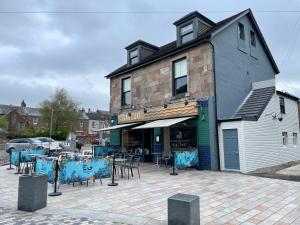 un edificio con mesas y sillas delante de él en Rooms Above Sugar Boat en Helensburgh