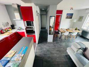 cocina y sala de estar con armarios rojos y mesa en L'appartement Lafayette rive gauche en Rouen
