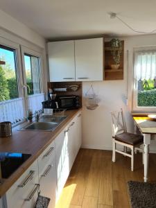 a kitchen with white cabinets and a sink and a table at Ferienhaus am See in Jabel