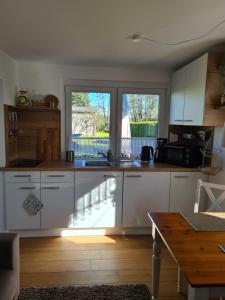 a kitchen with white cabinets and a large window at Ferienhaus am See in Jabel