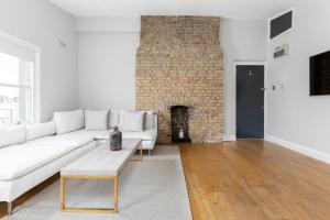 a living room with a white couch and a brick wall at The Notting Hill Apartment in London