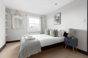 a white bedroom with a bed and a mirror at The Notting Hill Apartment in London