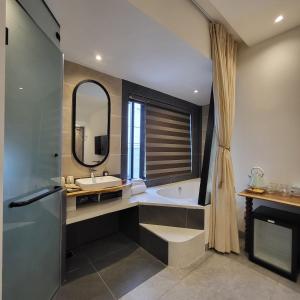 a bathroom with a tub and a sink and a mirror at Santori Villa My Khe Beach in Da Nang