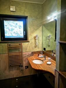 baño con lavabo y TV en la pared en ALBERGO BALDAZZI 1916 en Zavattarello