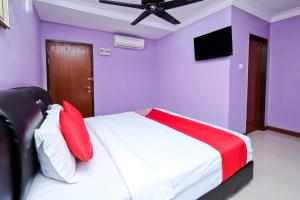 a bedroom with purple walls and a bed with red and white pillows at OYO 714 Arina Hotel in Bangi