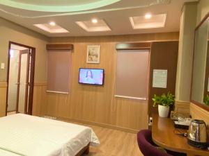 ein Krankenhauszimmer mit einem Bett und einem TV an der Wand in der Unterkunft Nhu Y Hotel in Ho-Chi-Minh-Stadt