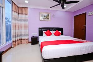 a bedroom with purple walls and a bed with red pillows at OYO 714 Arina Hotel in Bangi