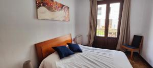 sypialnia z łóżkiem z niebieskimi poduszkami i oknem w obiekcie Somos Mar w Pampelunie