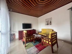 ein Wohnzimmer mit 2 Stühlen und einem TV in der Unterkunft appartements meublés à Logbessou in Douala