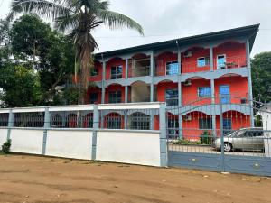 un edificio rosso con una recinzione di fronte di appartements meublés à Logbessou a Douala