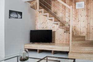 a living room with a tv and a wooden staircase at Baltica Mielenko - domki apartamentowe nad morzem in Mielenko