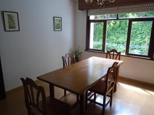 a dining room table with chairs and a large window at Piso céntrico Pontedeume in Puentedeume