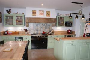 a kitchen with green cabinets and a wooden table at La Kerandière in Tonquédec