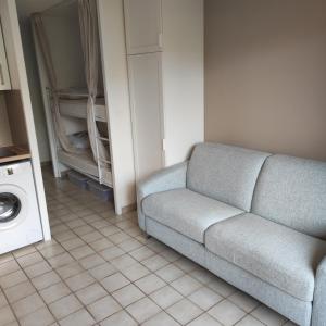 - un salon avec un canapé et un lave-linge dans l'établissement studio cabine quatre couchages classé 2 étoiles, à Bormes-les-Mimosas