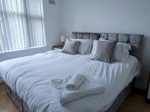 a large white bed with two towels on it at Pass the Keys Spacious Comfortable 3 Bedroom House in Birmingham
