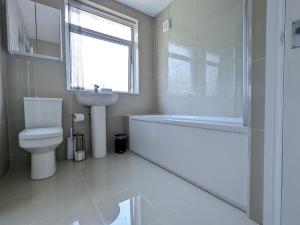 a bathroom with a tub and a toilet and a sink at Pass the Keys Spacious Comfortable 3 Bedroom House in Birmingham