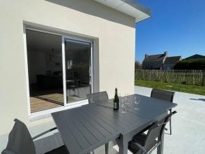 - une table en bois avec une bouteille de vin et des chaises dans l'établissement La Grenouillère, à Cléder