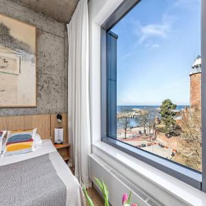 sypialnia z dużym oknem z widokiem na ocean w obiekcie Apartamenty z widokiem na morze i dziedziniec, parking BalticON Morska 6 w Kołobrzegu