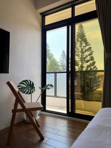 ein Schlafzimmer mit einem Stuhl und einem Fenster mit einer Pflanze in der Unterkunft 默森民宿 in Huxi