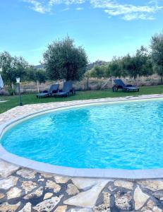 a large swimming pool with two chairs in a yard at Agriturismo il Portico in Capalbio