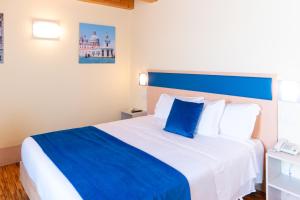 a bedroom with a large bed with blue and white pillows at Hotel Autoespresso Venice - Atika & Atif in Marghera