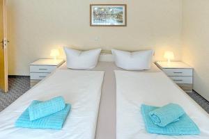 ein großes weißes Bett mit zwei blauen Kissen darauf in der Unterkunft Ferienwohnung Hibiskus in Lübbenau