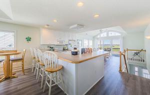 a kitchen with white cabinets and a bar with chairs at Shell Town in Nags Head