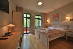 a bedroom with a bed and a desk and windows at Villa Alexandra in Świnoujście