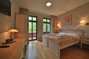 Schlafzimmer mit einem Bett, einem Schreibtisch und Fenstern in der Unterkunft Villa Alexandra in Świnoujście