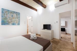 ein weißes Schlafzimmer mit einem Bett und einem Fernseher in der Unterkunft Designer HOME with COMFY SOFA in central Valletta by 360 Estates in Valletta