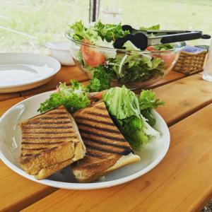 ein Sandwich und Salat auf einem Teller auf einem Tisch in der Unterkunft Glanchette岡山∼グランピング＆オートキャンプ∼ 