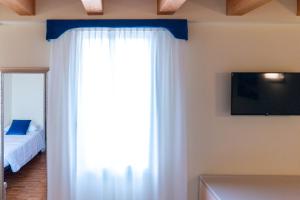 a bedroom with a white curtain and a tv at Hotel Autoespresso Venice - Atika & Atif in Marghera